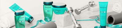 Three bottles of Kerastase hair care products from the Resistance line are displayed on a soft surface, with a measuring tape nearby.