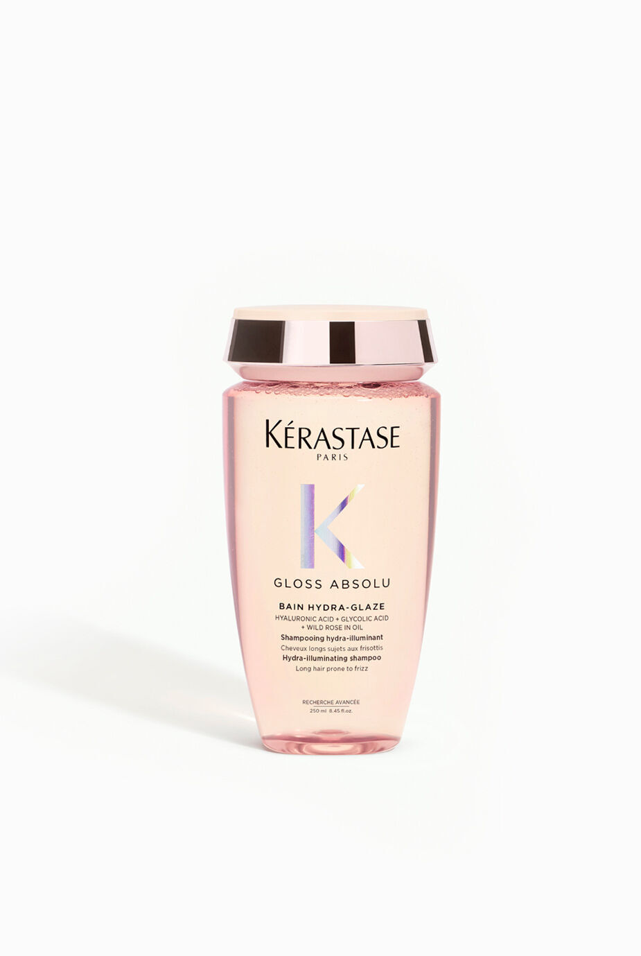 A bottle of Kerastase Gloss Absolu Bain Hydra-Glace shampoo, featuring a pink container with a gold lid and label.