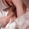 A person wearing a white satin shirt is gently styling their long hair.