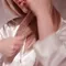 A person wearing a white satin shirt is gently styling their long hair.