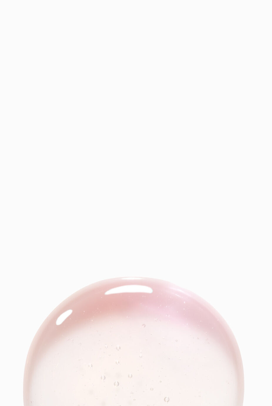 A close-up of a translucent, iridescent bubble with a soft pink hue, set against a plain white background.