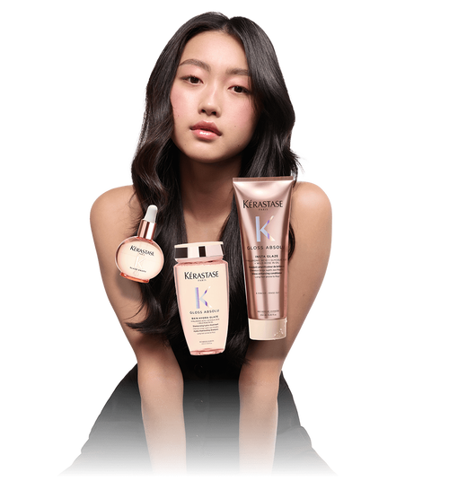 A model with long, wavy hair poses with three Kerastase hair care products, including a serum, a shampoo, and a conditioner. The background is transparent, focusing on the model and the products.