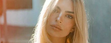 A close-up portrait of a woman with long, blonde hair, looking directly at the camera with a natural expression.