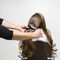 A person is brushing long hair of another person, who is seated and facing away.