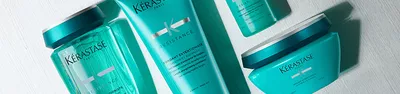 A close-up image of Kerastase hair care products, featuring two turquoise bottles labeled "Resistance" and "Fondant Extentioniste."