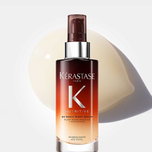 Bottle of Kerastase 8H Magic Night Serum with a creamy texture background, showcasing a nourishing hair care product.