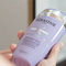 A person holding a bottle of Kerastase purple shampoo with a sleek design and holographic label.
