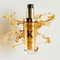 The new refillable Elixir Ultime is surrounded by beautiful golden hair oil drops and texture.