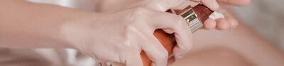 A close-up image of a hand squeezing a pump bottle, dispensing a creamy substance.