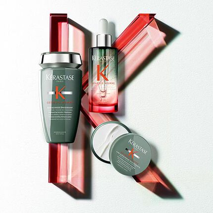 A flat lay of three skincare products, including a bottle with a dropper, a jar, and a tube, arranged on a light-colored background with red decorative elements.
