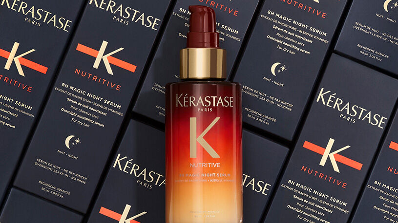 Bottle of Kerastase 8H Magic Night Serum surrounded by its sleek, navy packaging, highlighting the product's luxurious design.
