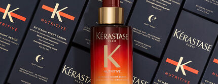 Bottle of Kerastase 8H Magic Night Serum surrounded by its sleek, navy packaging, highlighting the product's luxurious design.