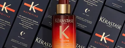 Bottle of Kerastase 8H Magic Night Serum surrounded by its sleek, navy packaging, highlighting the product's luxurious design.