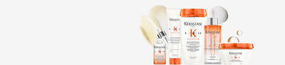 An arrangement of Kerastase hair care products including shampoos, conditioners, a serum, and a mask, all in sleek bottles and jars with a modern design. The products feature a white and orange color scheme.