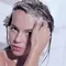 A person with wet hair is applying shampoo while looking directly at the camera. Water is dripping down their face and shoulders.