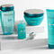 A flat lay of Kerastase hair care products, including a shampoo, conditioner, serum, and treatment, arranged on a textured surface with a ruler marking in the background.