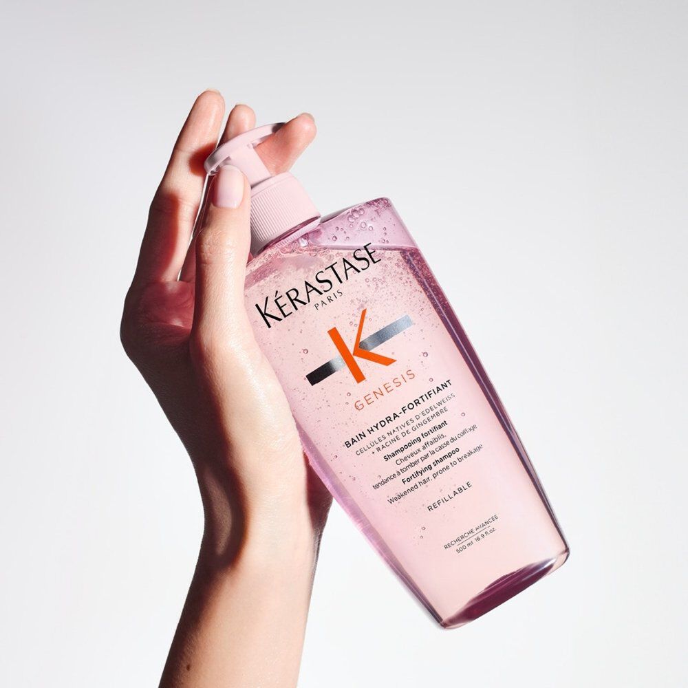 A woman’s hand holding a refillable bottle of Genesis Bain Nutri-Fortifiant Shampoo