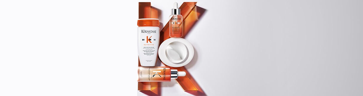 Alt text: A flat lay arrangement of four hair care products from the Kerastase Nutritive line, displayed against a light background, with an artistic orange "K" shape formed by the products.