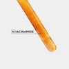 Close-up of a test tube containing a golden liquid with bubbles, labelled \'Niacinamide\' prominently.