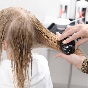 Person gently brushing long hair, demonstrating gentle brushing technique to prevent hair breakage
