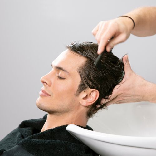 Male model with a receding hairline having his hair washed in a basin