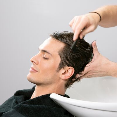 Male model with a receding hairline having his hair washed in a basin