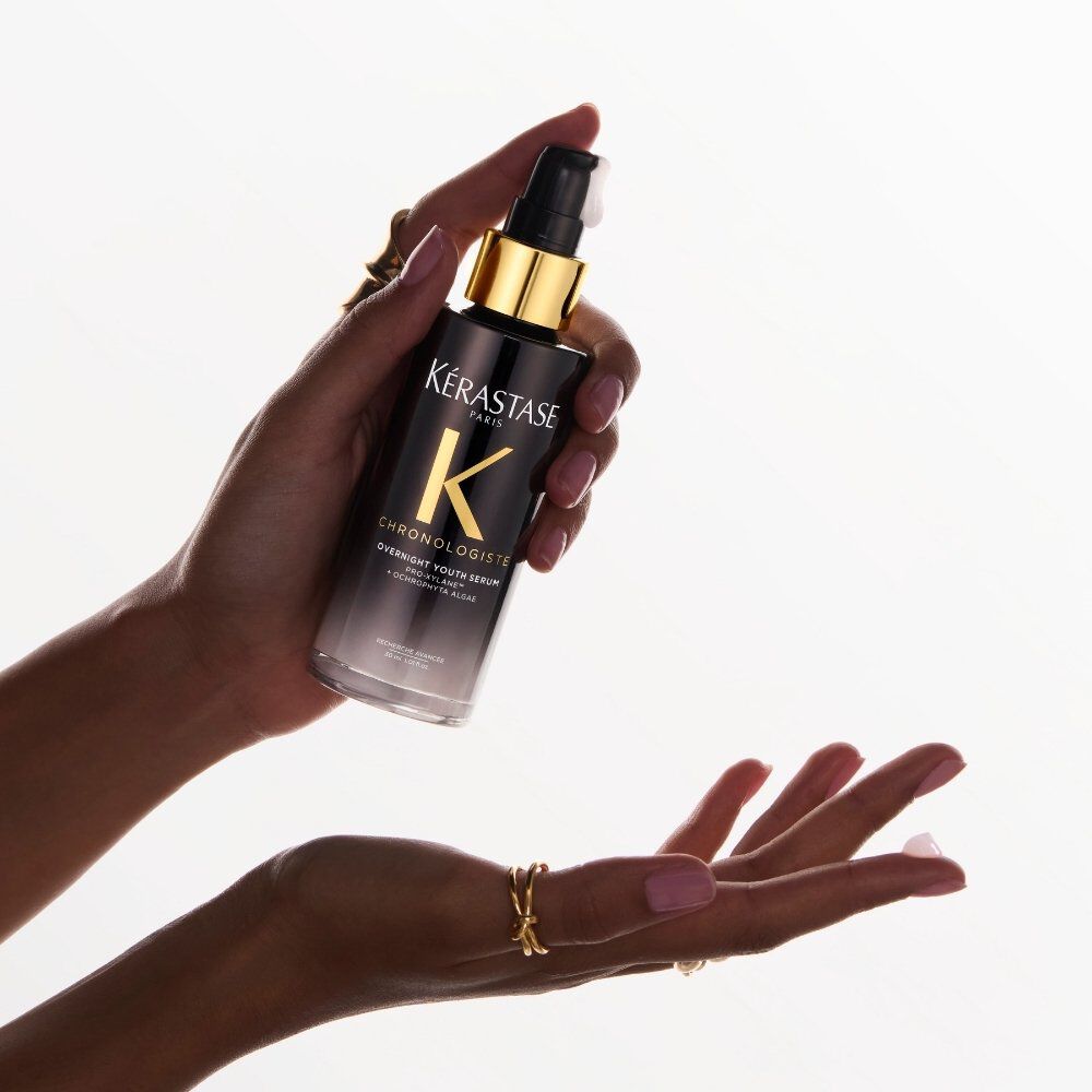 A woman’s hand holds Chronologiste Bain Regenerant Shampoo, an anti- ageing haircare shampoo.