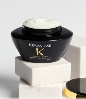 SHOT OF A BLACK AND GOLD BOTTLE ON A PODIUM WITH THE LID OFF