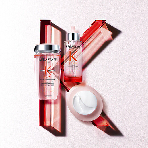 Kérastase haircare products arranged artistically, featuring a shampoo, serum, and cream against a textured background.