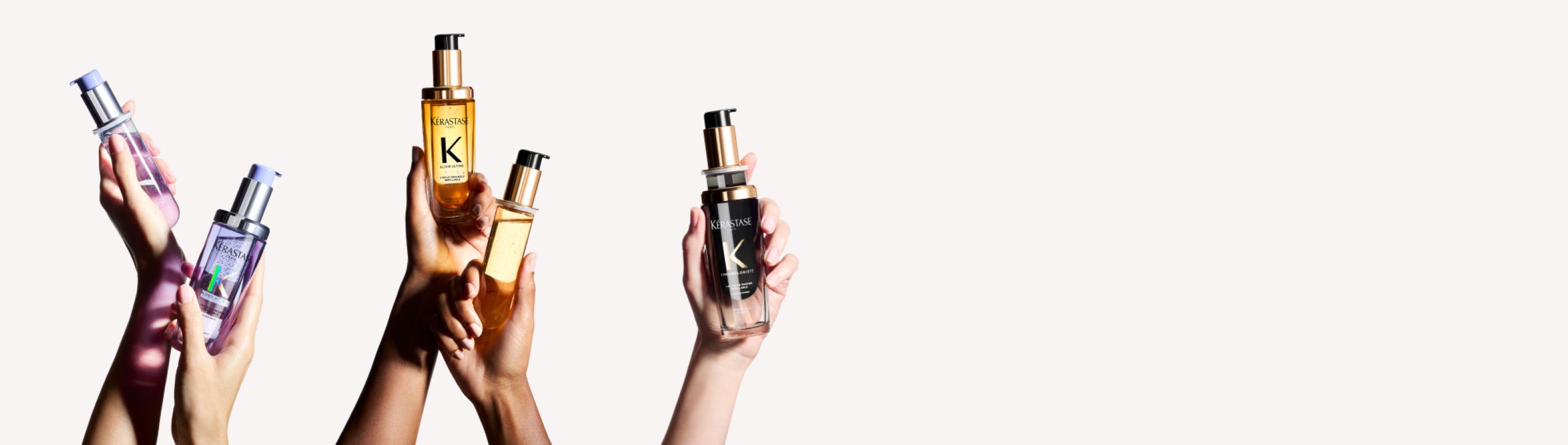 A diverse group of hands holding various stylish skincare bottles against a minimalist background.